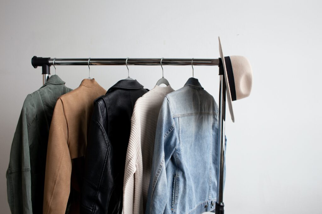 Photo of jackets hanging on a clothing rack with a hat on the end