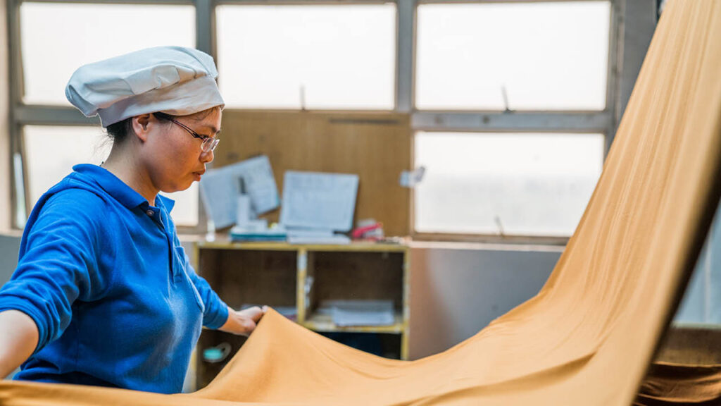 Photo of a female factory worker inspecting draped fabric