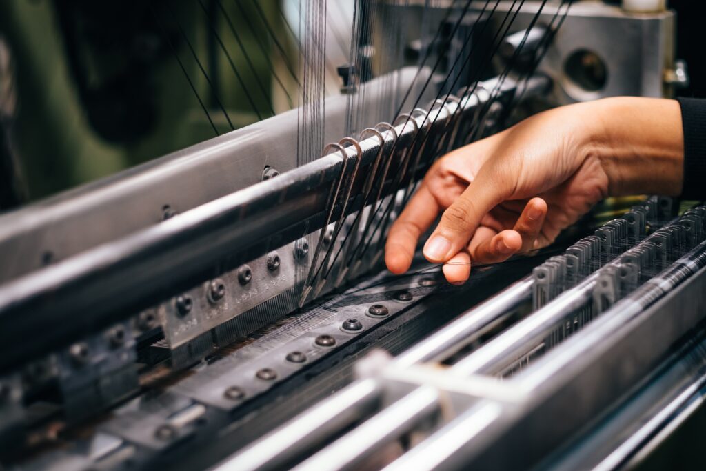 Photo of a hand working a large factory sewing machine