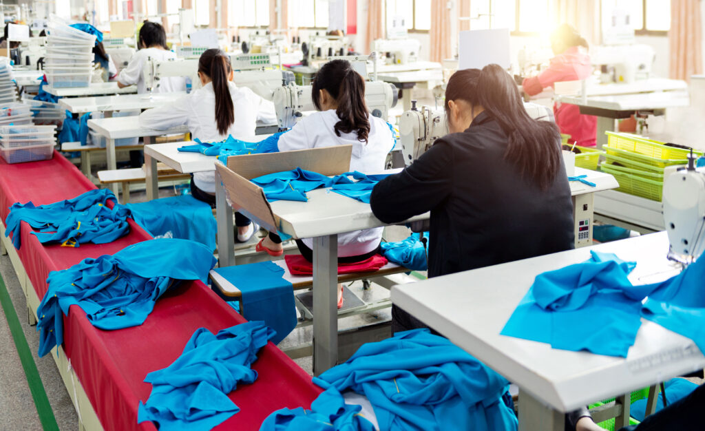 Rear view of chinese female blue collar workers working in clothing factory in a row