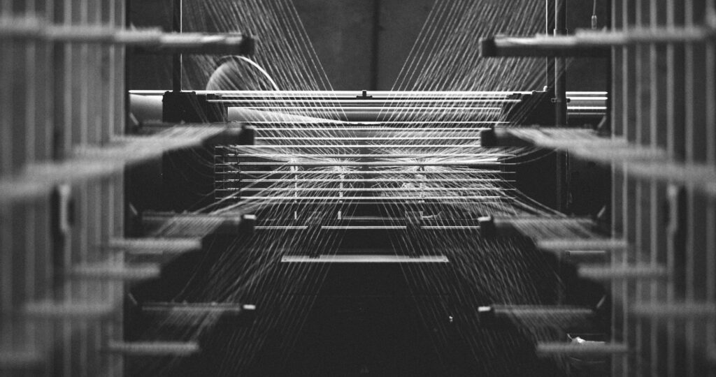 Black and white photo of a textile factory machine weaving close up