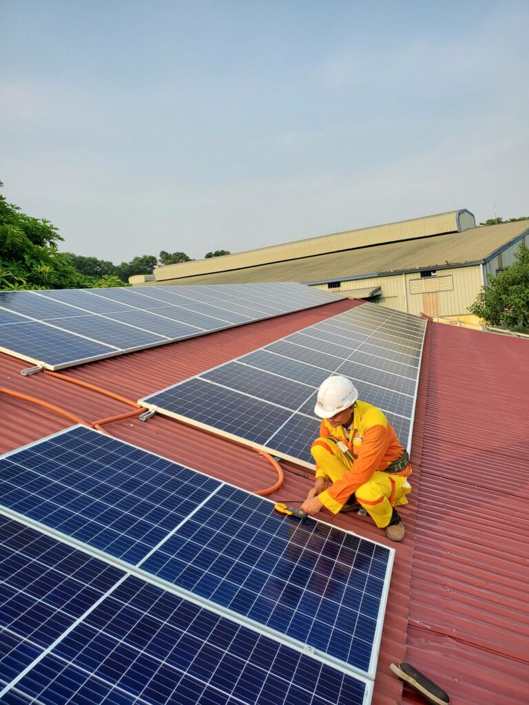 Photo of a worker installing solar panels on a rooftop