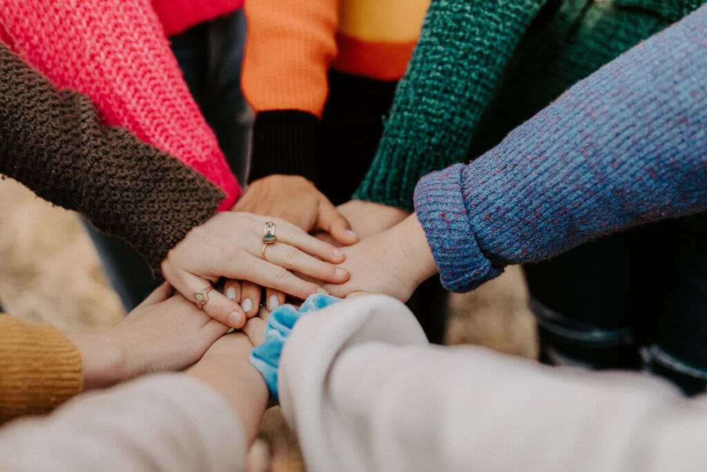 Closeup photo of seven people's hands coming together in the middle of a circle