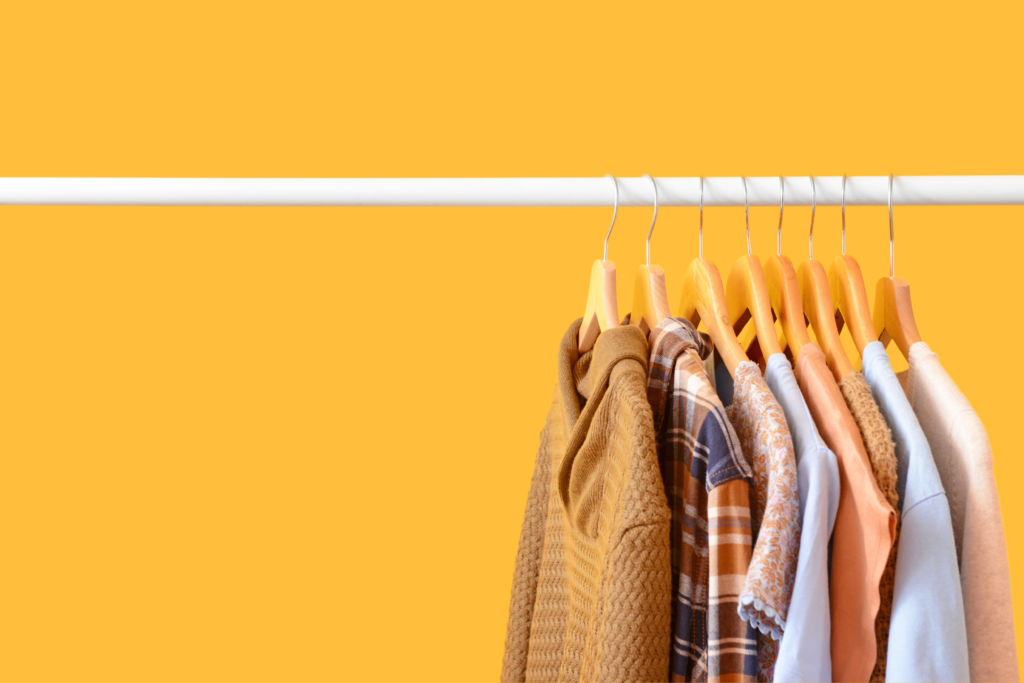Rack with hanging clothes on a bright yellow background