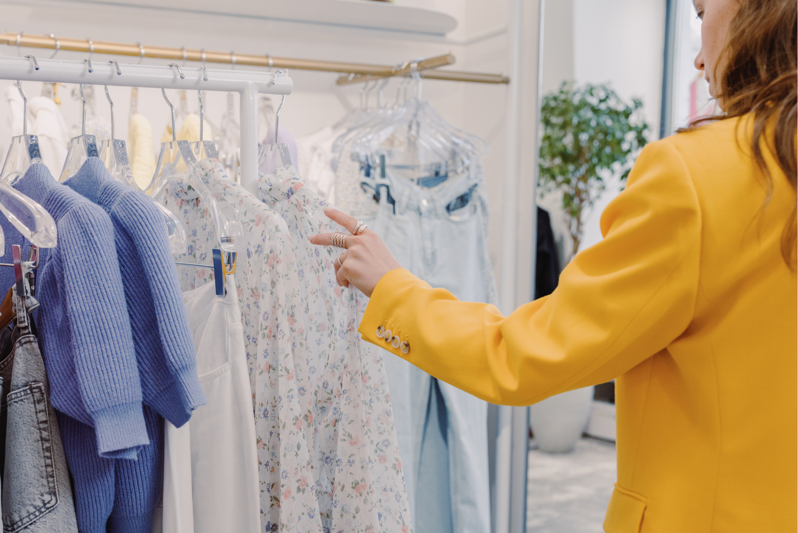 Woman in yellow blazer browsing a rack of clothing