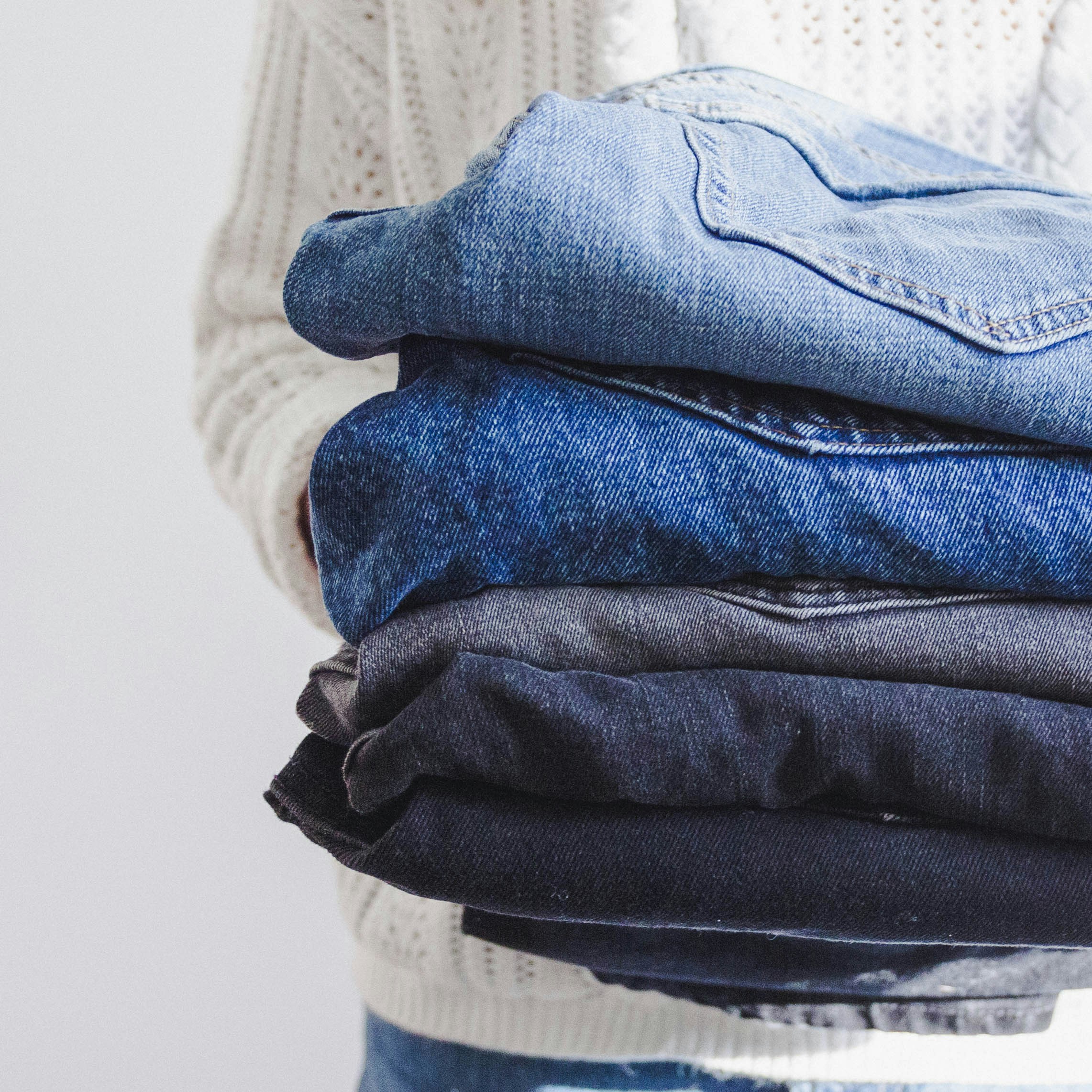 Close up of person holding folded stack of jeans