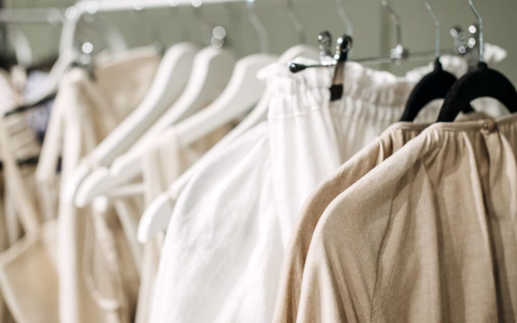 Close up photo of white and tan clothes hanging on a rack