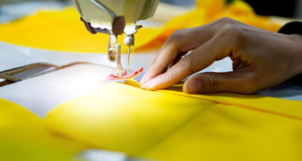 Hand sewing a yellow material on machine