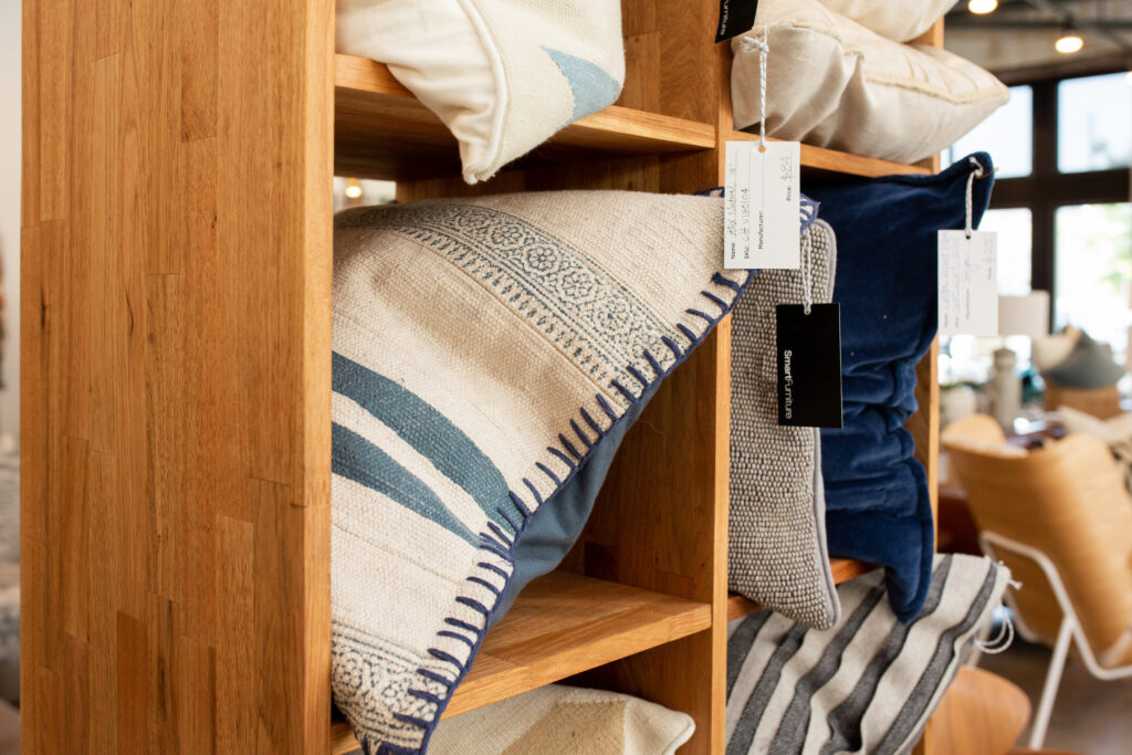 Assorted throw pillows in wooden shelf at store