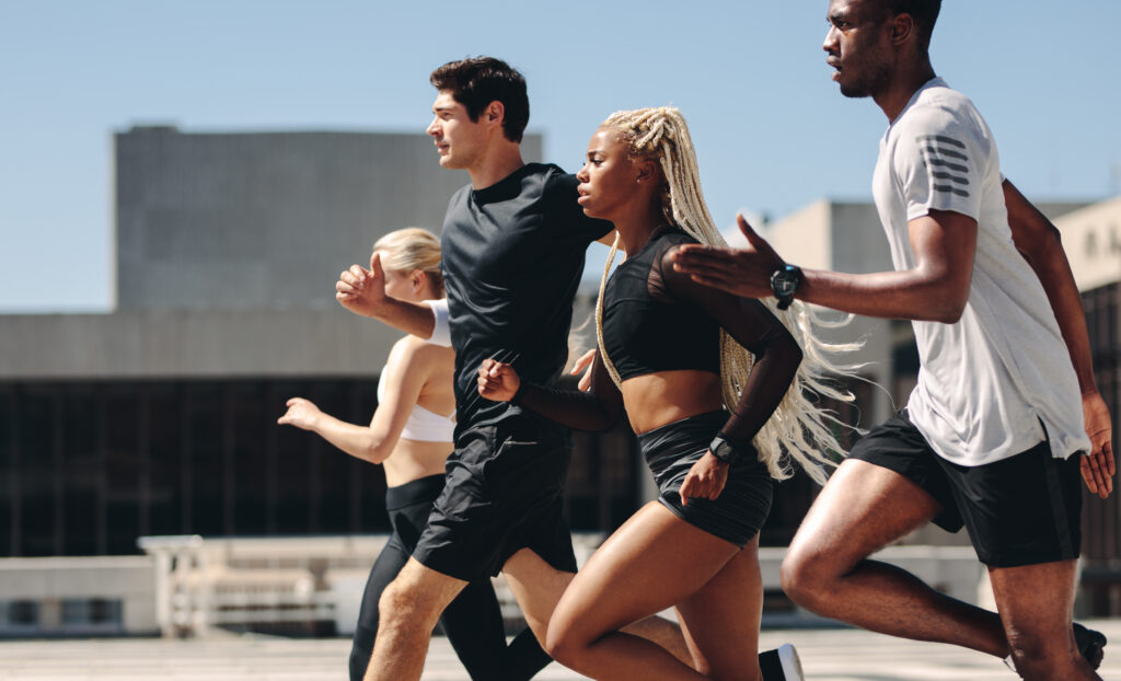 Healthy people running together in city. Runners training together outdoors in morning.
