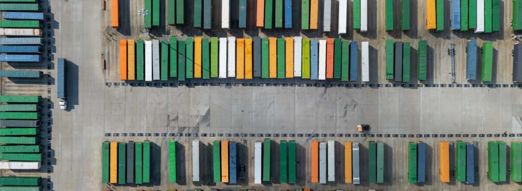 Freight containers stacked in an industrial yard with a truck and forklift moving cargo in Texas.